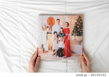 hands with closed photobook on a white background. family photo shoot  88109102