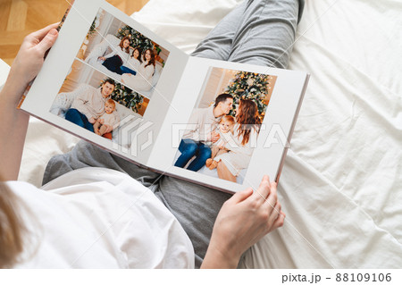 top view woman holds photobook in hands while sitting in bed.family photo shoot  88109106