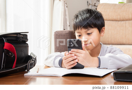 勉強中にスマホを見る小学生の男子 88109911