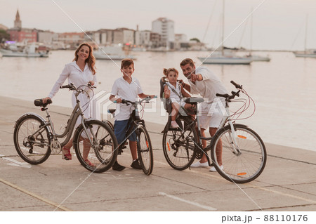 The happy family enjoys a beautiful morning by the sea riding a bike together and spending time together. The concept of a happy family The happy family enjoys a beautiful morning by the sea riding a bike together and spending time together. The concept of a happy family 88110176
