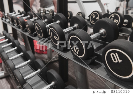 Closeup of kilogram dumbbells placed on a dumbbell rack at the gym. Weight training equipment. 88110319