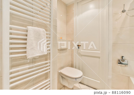 Bathroom with walls of flesh-colored tiles, toilet and heater in a modern house Bathroom with walls of flesh-colored tiles, toilet and heater in a modern house 88116090