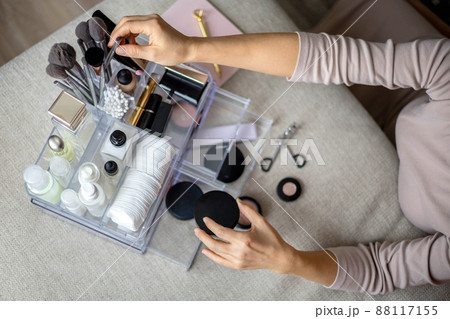 Closeup female hands putting luxury cosmetic into acrylic box with drawer storage organization Closeup female hands putting luxury cosmetic into acrylic box with drawer storage organization 88117155