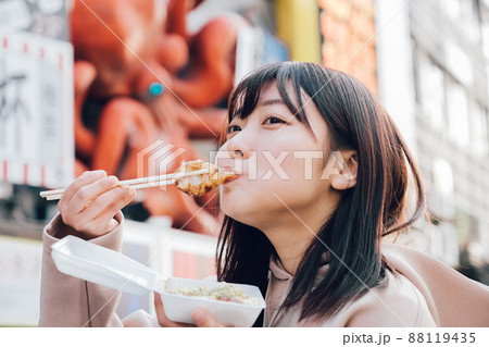 大阪ミナミでたこ焼きを食べる女性 88119435
