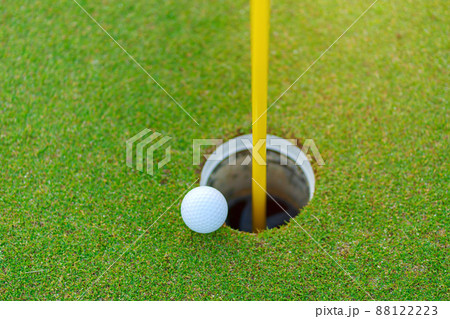 Golf ball on lip of cup at golf court Golf ball on lip of cup at golf court 88122223