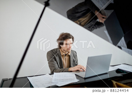 Man studying to play piano online Man studying to play piano online 88124454