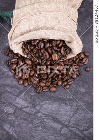 Heap of dark roasted coffee grains in jute bag. Place for text 88124467