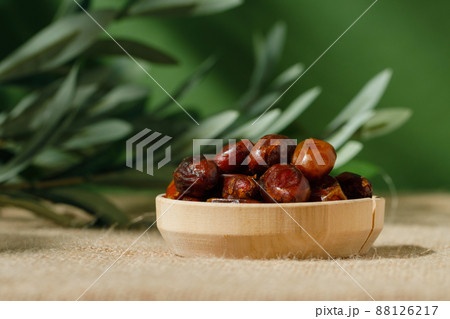 dried dates in a wooden plate on a green background on a sunny day. dried dates in a wooden plate on a green background on a sunny day. 88126217