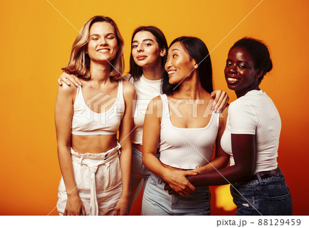 diverse multi nation girls group, teenage friends company cheerful having fun, happy smiling, cute posing on yellow background, lifestyle people concept, african-american, asian and caucasian 88129459