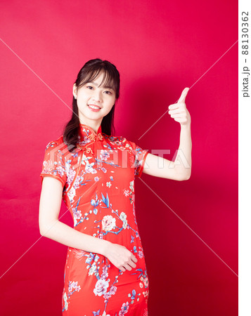 Asian woman wearing traditional cheongsam qipao dress with gesture of introduce isolated on red background. 88130362