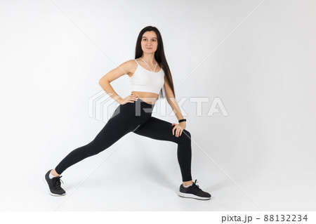 Fitness girl doing stretching workout on white background. Attractive brunette woman in fashionable sportswear exercising. Healthy lifestyle, sport concept, Full length view Fitness girl doing stretching workout on white background. Attractive brunette woman in fashionable sportswear exercising. Healthy lifestyle, sport concept, Full length view 88132234
