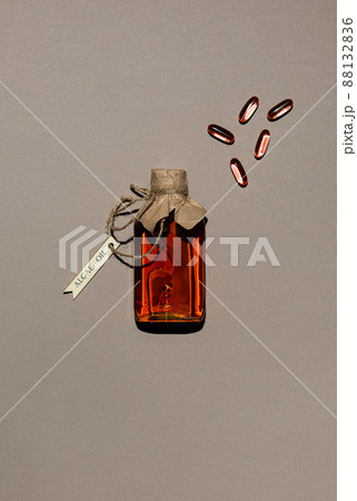 Glass bottle with algae oil and few capsules on brown paper Glass bottle with algae oil and few capsules on brown paper 88132836