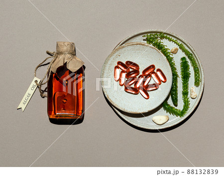 Glass bottle with algae oil, seaweed and jelatin capsules on brown paper Glass bottle with algae oil, seaweed and jelatin capsules on brown paper 88132839