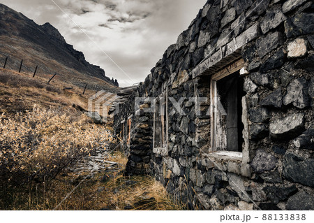 An old abandoned stone building at the foot of the mountain. 88133838