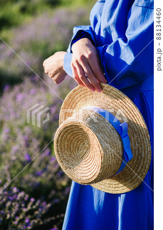 Girl holding a straw hat in hands Girl holding a straw hat in hands 88134460