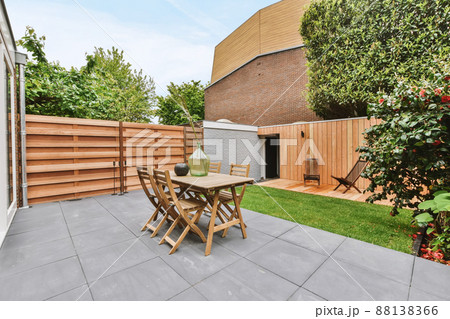 Stylish and well-maintained courtyard of the house with wooden table and chairs and a fresh lawn 88138366