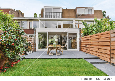 Stylish and well-maintained courtyard of the house with wooden table and chairs and a fresh lawn 88138367