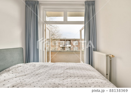 The interior of a small bedroom with access to the balcony of a modern cozy house 88138369