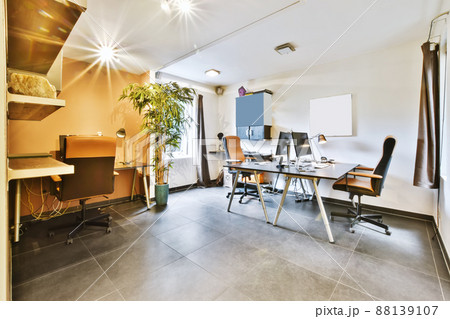 Cozy work room with two desks with computers and a window Cozy work room with two desks with computers and a window 88139107