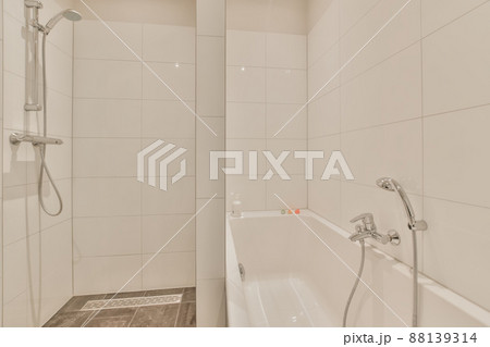 Bathroom with shower and bathtub surrounded by white tiles and marble floor Bathroom with shower and bathtub surrounded by white tiles and marble floor 88139314