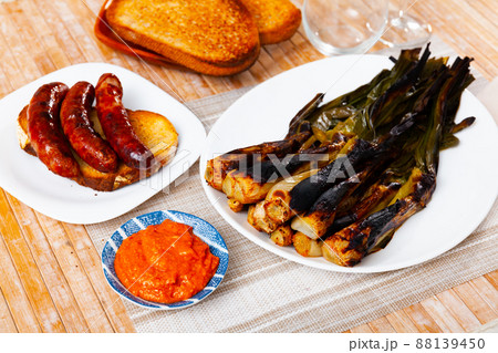 Calcot with romesco sauce and grilled botifarra Calcot with romesco sauce and grilled botifarra 88139450