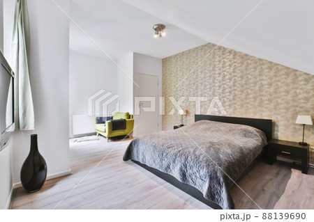 Cozy bedroom with a bed covered with a gray blanket and parquet floor Cozy bedroom with a bed covered with a gray blanket and parquet floor 88139690