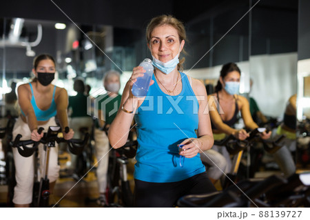 Adult woman in mask with fitness bike in gym 88139727
