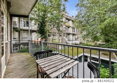 Long balcony with a table and two chairs overlooking the green trees 88140022