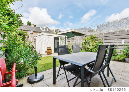 Amazing courtyard of the house with a lawn and a black table with chairs 88140246