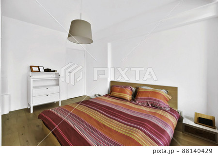 The interior of an amazing bedroom with a soft bed covered with a bard bedspread and a cylinder chandelier 88140429
