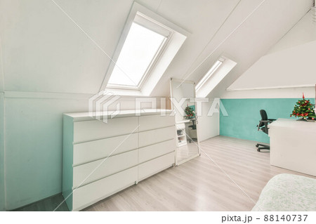 Modern room in the attic of a house with white furniture and white walls 88140737