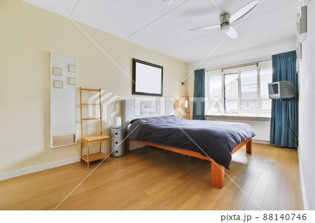 A magnificent large bedroom with a soft bed covered with a black coverlet and a large window 88140746