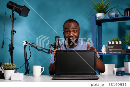 Portrait of reviewer showing new model laptop display technology on desk in vlogging studio using professional microphone to talk to audience. Vlogger reviewing portable computer for social media. Portrait of reviewer showing new model laptop display technology on desk in vlogging studio using professional microphone to talk to audience. Vlogger reviewing portable computer for social media. 88140951