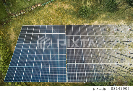 Top view of solar module fading away and shifting into metal supporting structure. Transition between solar panel and metal poles in grassy field with green trees. Concept of alternative energy. Top view of solar module fading away and shifting into metal supporting structure. Transition between solar panel and metal poles in grassy field with green trees. Concept of alternative energy. 88145902