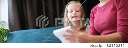 Mom sits on the couch and teaches her daughter to draw 88150832
