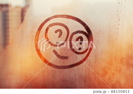 Happy smile face with question mark in their eyes painted on sunset window flooded with raindrops on blur glass background in city Happy smile face with question mark in their eyes painted on sunset window flooded with raindrops on blur glass background in city 88150853