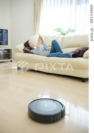 お掃除ロボットでフロア清掃中にスマホを見る主婦 お掃除ロボットでフロア清掃中にスマホを見る主婦 88154860