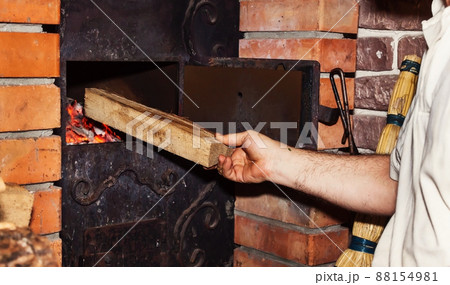 Man puts firewood in a stove, close-up of a hand 88154981