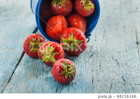 Fresh ripe strawberries in a blue bucket on a wooden background Fresh ripe strawberries in a blue bucket on a wooden background 88156166