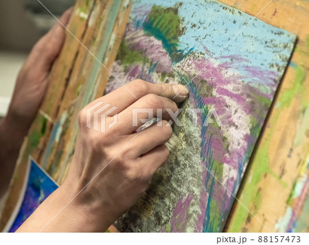 Hand is in motion. Drawing with pastels close-up. Woman drawing beautiful crocus flowers with soft pastel at table. Close up. 88157473