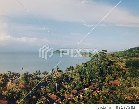 Aerial view of red roofs of houses, palms and ocean. Tropical landscape on island Aerial view of red roofs of houses, palms and ocean. Tropical landscape on island 88157583