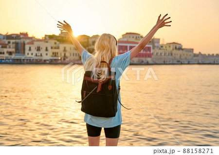 Happy blonde female with backpack on sea promenade, back view 88158271