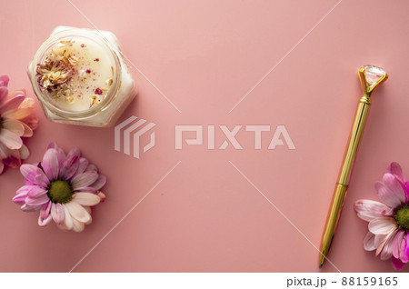 Pink quartz face roller with aroma candle and flower on pink background. Minimal self care concept 88159165