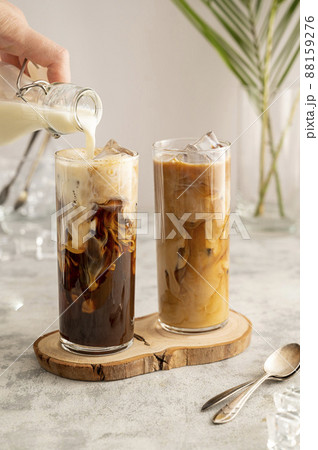 Iced coffee in glass. Pouring milk in glass with coffee. Summer drink. Iced coffee in glass. Pouring milk in glass with coffee. Summer drink. 88159276