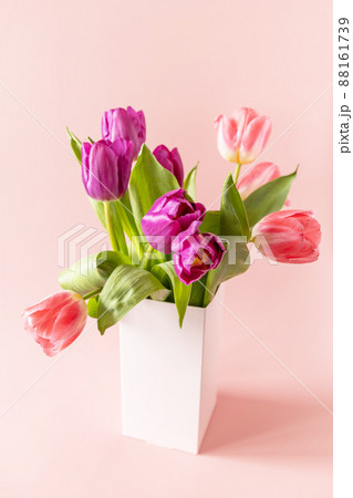 Bouquet of pink and purple tulips with colorful quail eggs over pink background. Mother's day holiday concept. Bouquet of pink and purple tulips with colorful quail eggs over pink background. Mother's day holiday concept. 88161739