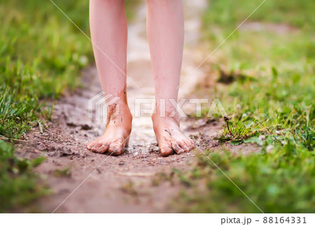 Barefoot girl walks through a puddles of water after the summer rain. Barefoot girl walks through a puddles of water after the summer rain. 88164331
