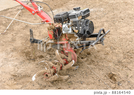 Small farm tractor plows the ground, the work of a walk-behind tractor 88164540