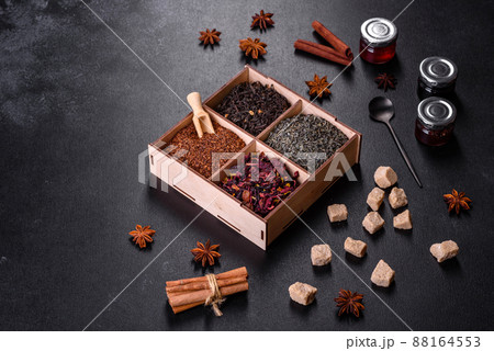 Several kinds of dry black tea with bergamot, rooibos, green and frame in a wooden box on a black concrete background 88164553