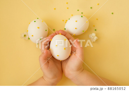 Easter eggs in the hands of a child. The religious holiday of Easter. The decor of Easter eggs. Eggs with polka dots on a yellow background. Easter eggs in the hands of a child. The religious holiday of Easter. The decor of Easter eggs. Eggs with polka dots on a yellow background. 88165052