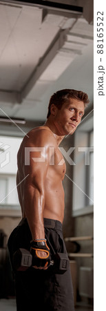 Strong muscular man holding a dumbbell in the gym Strong muscular man holding a dumbbell in the gym 88165522